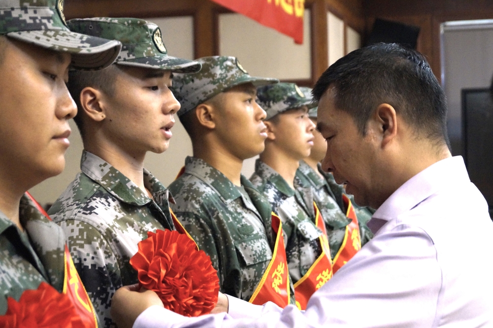 李志鵬為入伍學生佩戴大紅花并發放慰問品