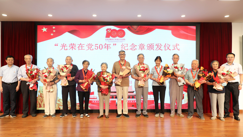 校領(lǐng)導(dǎo)為退休黨員頒發(fā)紀(jì)念章、獻(xiàn)花并合影留念