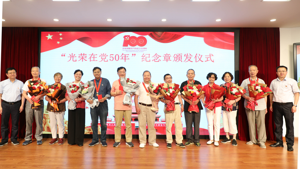 校領(lǐng)導(dǎo)為退休黨員頒發(fā)紀(jì)念章、獻(xiàn)花并合影留念