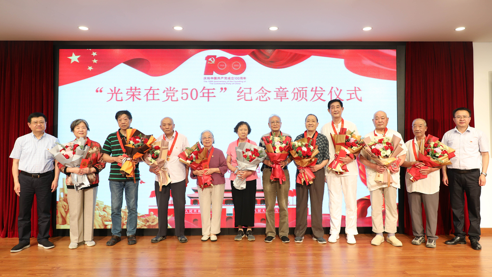 校領(lǐng)導(dǎo)為退休黨員頒發(fā)紀(jì)念章、獻(xiàn)花并合影留念