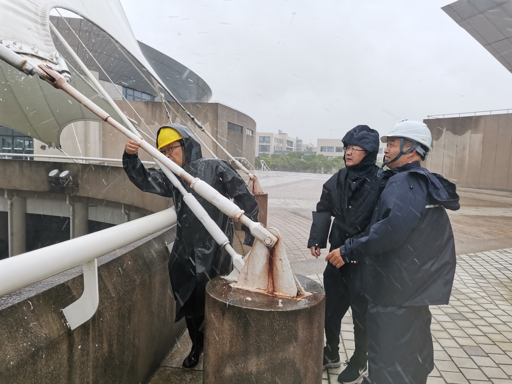 工作人員風雨中檢查體育館桅桿幕結構拉索緊固件